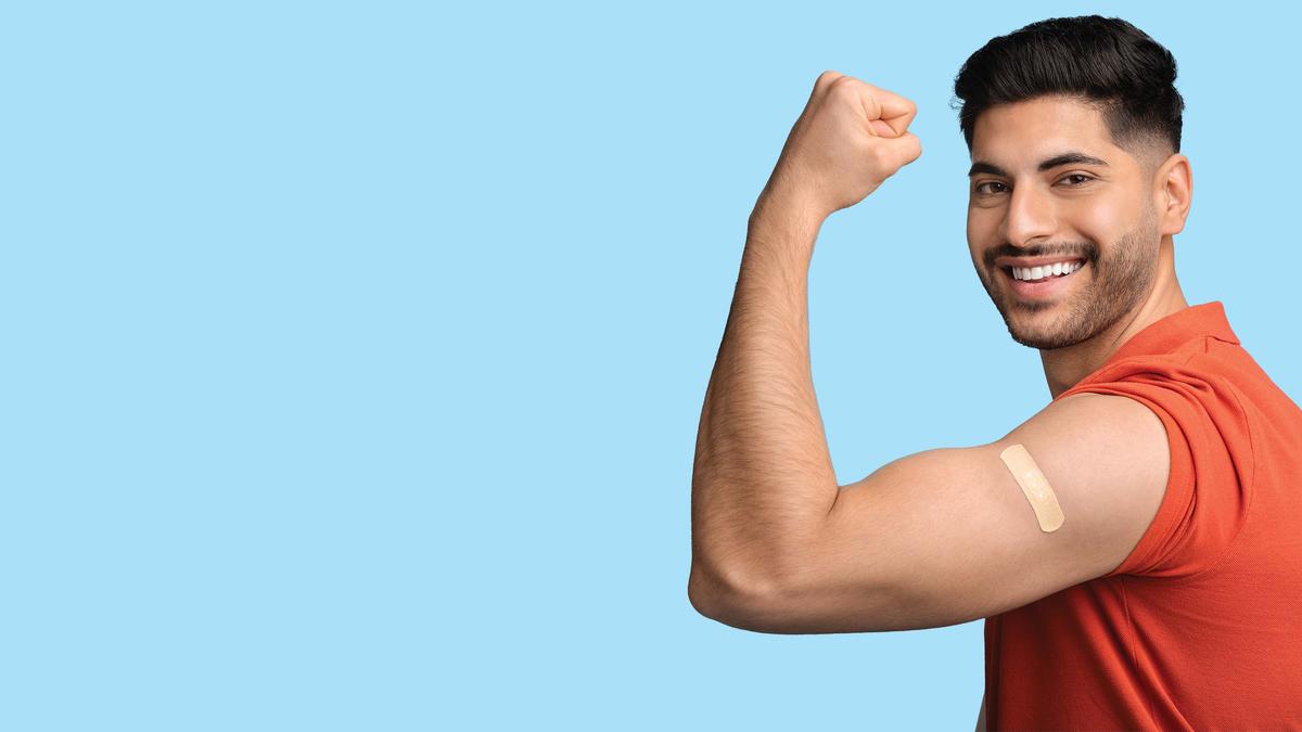 Man holding up his arm to show off his flu shot bandaid