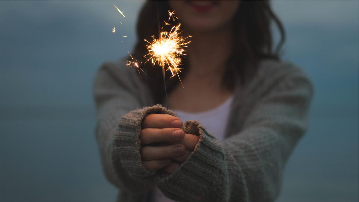 [a close up of a person's hands holding a sparkler with a blurred background]