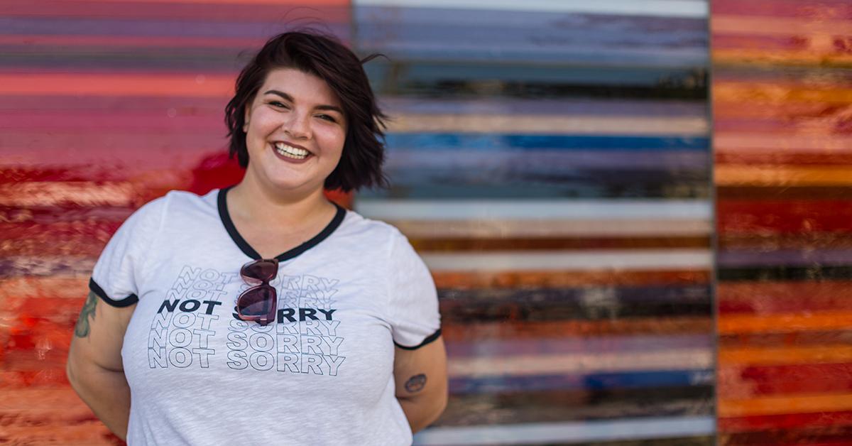 Planned Parenthood Iowa storyteller Isa smiles brightly in a shirt that says "not sorry."