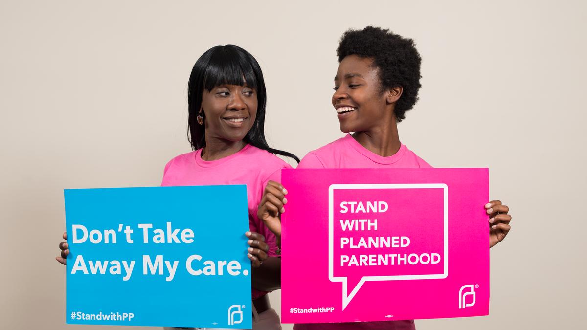 Volunteers holding blue and pink Planned Parenthood signs